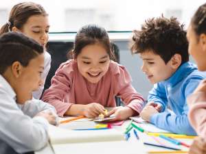 School kids learning over a table looking at a smartphone.