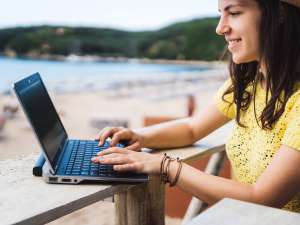 girl working on computer by a beach