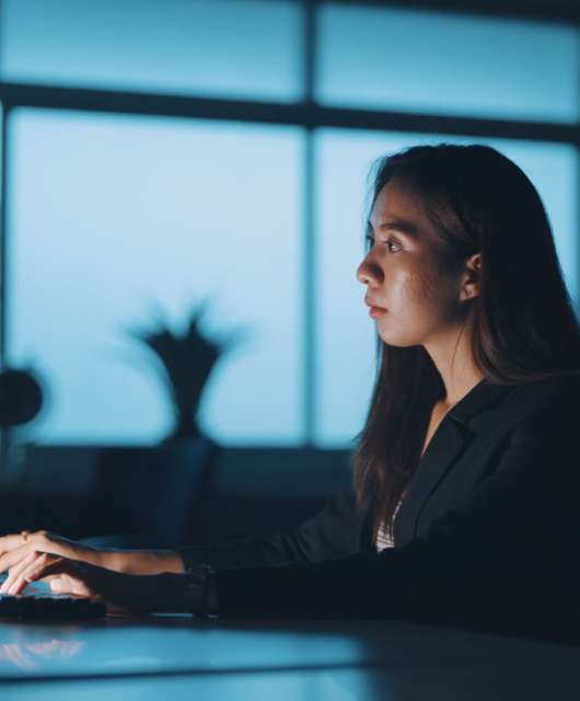 Women sitting in a dark room while typing on a computer.